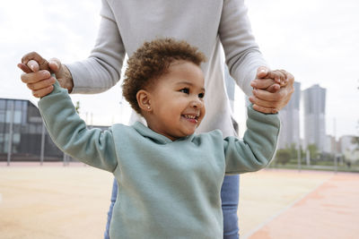 Cute girl holding hands of woman at sports field