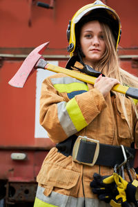 Portrait of female firefighter holding axe