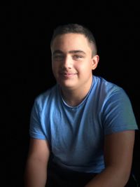 Portrait of a smiling young man against black background