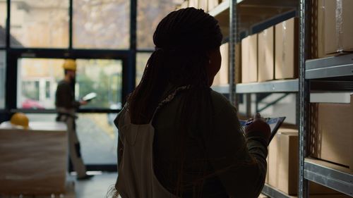 Rear view of woman looking through window