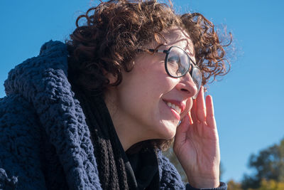 Portrait of young woman looking away against blue sky