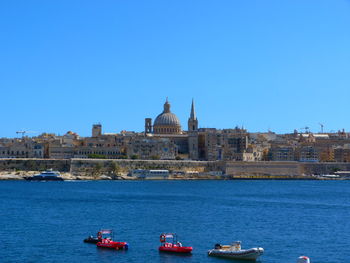 Boats sailing in river with buildings in background