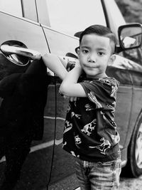 Portrait of cute boy standing by car