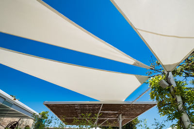 Low angle view of flags against clear blue sky