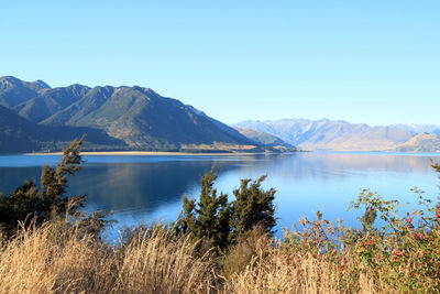 Scenic view of lake and mountains against clear blue sky