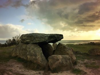 Rocks on field against sky during sunset