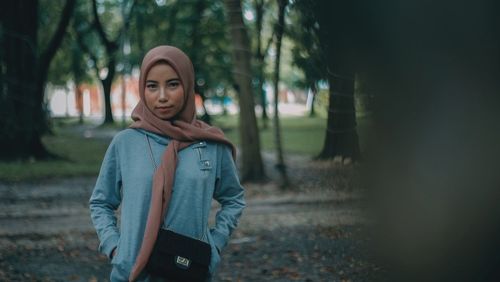 Portrait of young woman wearing hijab while standing at park