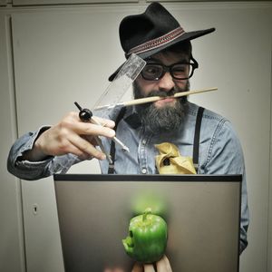 Painter with painting equipment and bell pepper against wall