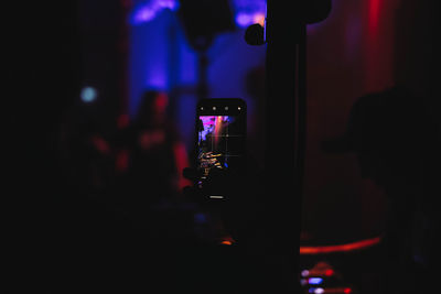 Man photographing illuminated smart phone at night