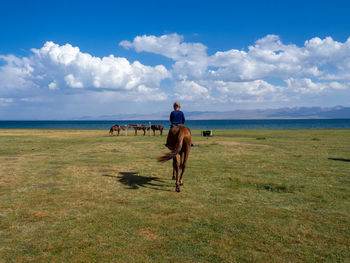 Rear view of woman walking on field against sky