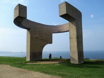 People on bridge over sea against sky