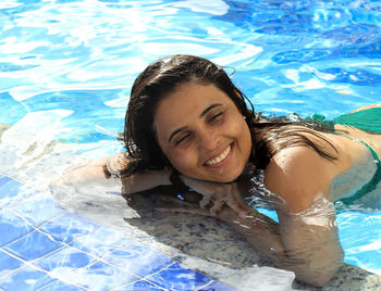 Smiling woman with closed eyes resting at swimming pool