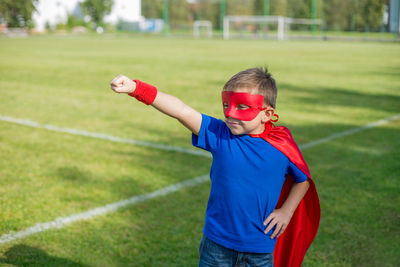 Boy in superman costume standing on field