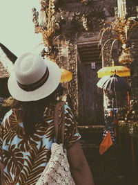 Rear view of woman wearing hat hanging from tree