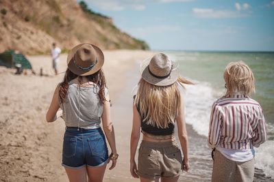 Rear view of friends standing on beach