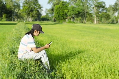 Asian woman using mobile phone beside the fields.