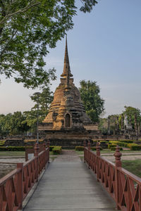 Walkway leading towards ruined pagoda against clear blue sky