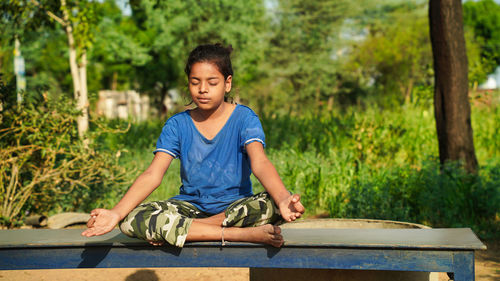 Positive cute little indian girl sitting on the roll mat. girls doing gymnastic exercises or exercis