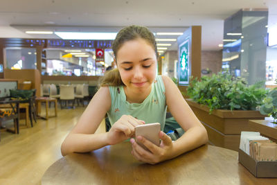 Young woman using phone on table