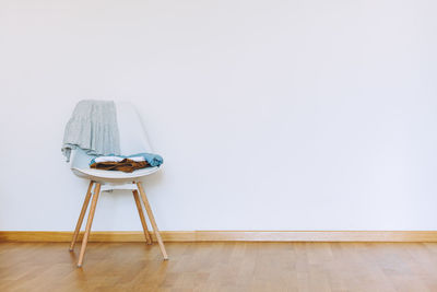 Empty chair on hardwood floor against wall at home