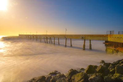 Pier over sea against sky at sunset