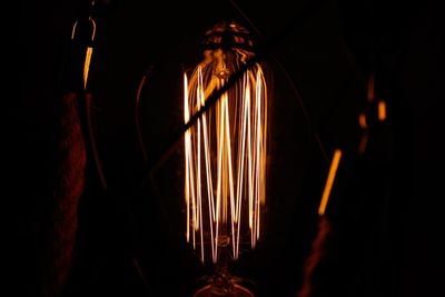 Close-up of illuminated lighting equipment against black background