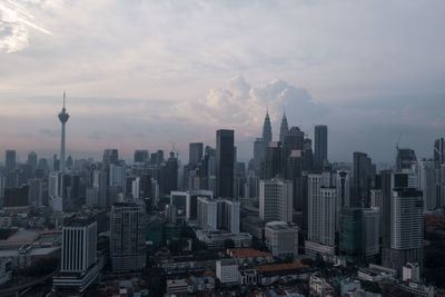 Aerial view of buildings in city against cloudy sky