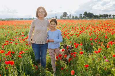 Mother and daughter walking in the poppy field with their dog