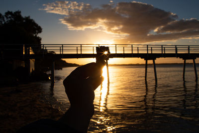 Silhouette man on bridge against sky during sunset