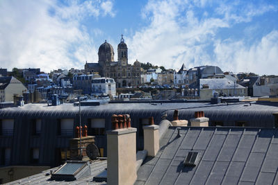 Buildings in city against cloudy sky