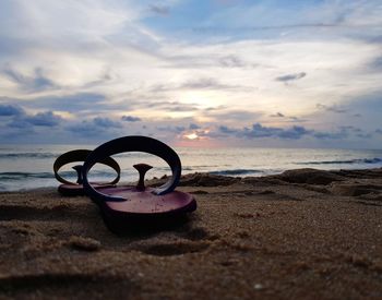 Sunglasses on beach against sky during sunset