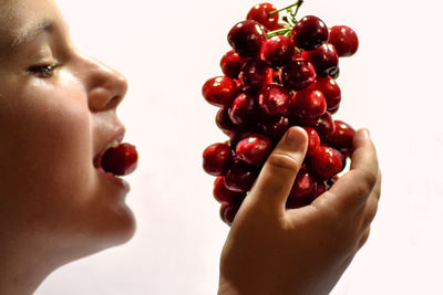 Close-up of woman holding strawberry over white background