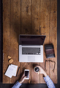 Man with coffee cup and smartphone at his desk