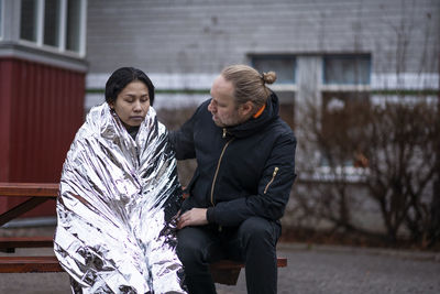 Man taking care of woman in emergency blanket