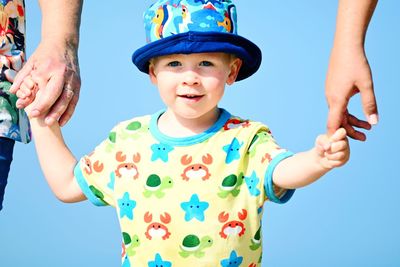 Portrait of happy boy standing against blue sky