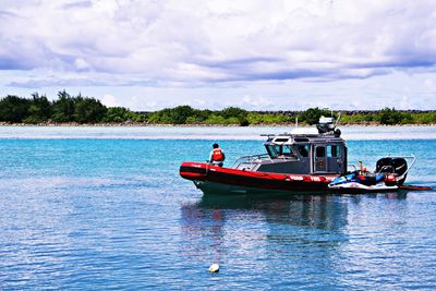 Boats in sea against cloudy sky