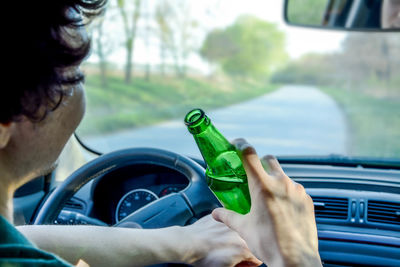 Close-up of man drinking beer while driving car