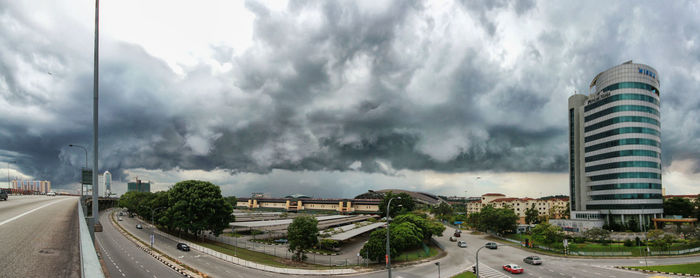 Panoramic view of city street against cloudy sky