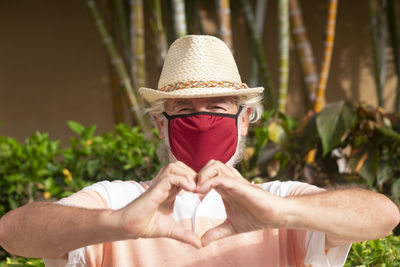 Portrait of smiling man making heart shape outdoors