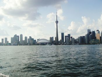 View of city by river against cloudy sky