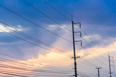 Low angle view of electricity pylon against sky during sunset