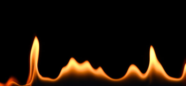 Close-up of burning candle against black background