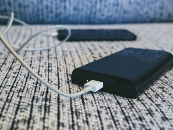 Close-up of smart phone connected to portable charger on table