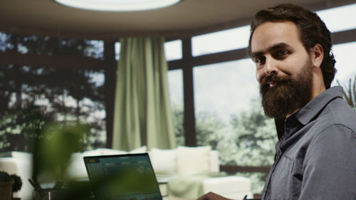 Side view of man using laptop while sitting at home