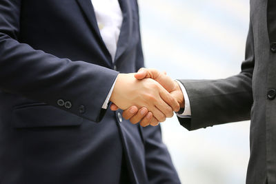 Midsection of businessmen shaking hands outdoors