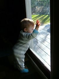 High angle view of baby boy looking through window at home