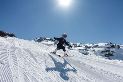 Person skiing on snow covered mountain against clear sky
