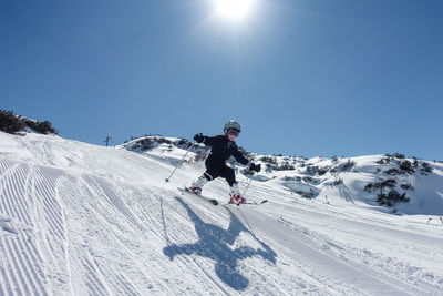 Full length of boy skiing on snow field against sky