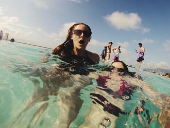 Young women in swimming pool against sky