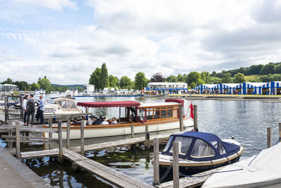 Boats moored on river in city against sky